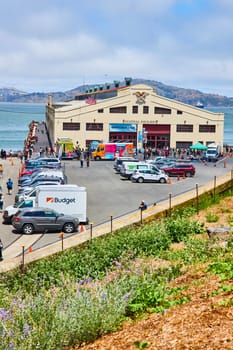 Image of Hilltop view of Festival Pavilion with crowd of people gathered around and view of bay