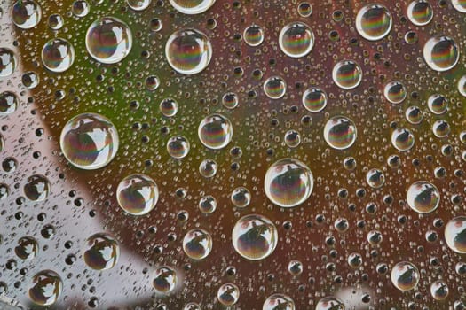 Image of Water drops on metallic surface with tiny reflective rainbows inside each drop