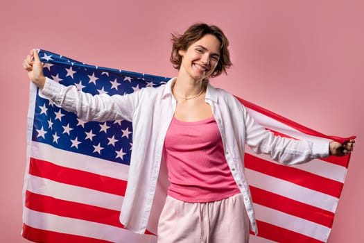 Smiling woman with national USA flag on pink background. American patriot, 4th of July - Independence day celebration, election, America, labor. US banner. High quality