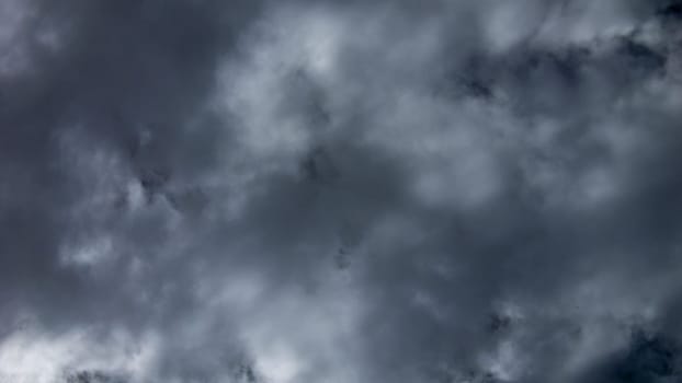 Dense, dark storm clouds loom overhead, casting shadows over a serene rural area as the afternoon light begins to fade, signaling the potential for rain.