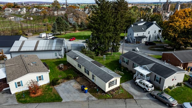 Various Mobile, Prefab, Manufactured, homes are seen in a rural setting with colorful autumn trees and a distant industrial area