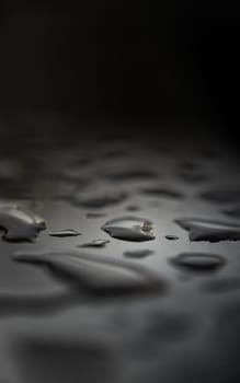 Detail of Water droplets caused by rain perched on the metallic surface. Rain water drops on a stainless steel handle, Natural Pattern of dew drops or raindrops on silver metal background for wallpaper poster and banner design, Selective focus.
