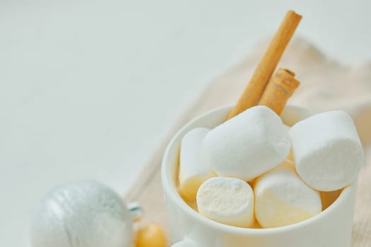 Cozy white mug with marshmallows and cinnamon sticks symbolizes warmth and comfort, evoking coziness