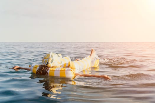 A person floats on a yellow and white inflatable raft in a calm sea.