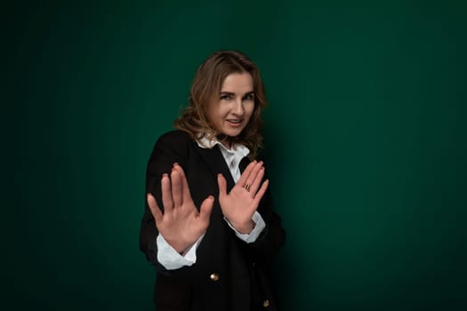 A woman wearing a black jacket stands with her hands outstretched in front of her. She appears to be reaching or gesturing towards something in the distance.