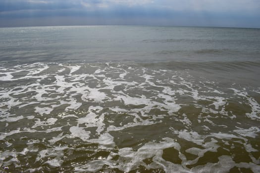 Beautiful landscape - turquoise colored sea water, sand, sky. The waves are on the sea to the shore. The Beach And Splashing Waves