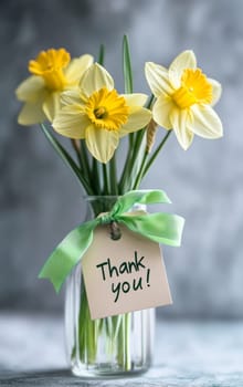 Bouquet of daffodils in a glass vase on a gray background. The inscription "thank you" on a bouquet of flowers. High quality photo
