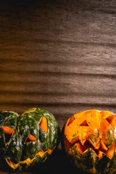 Two small pumpkins carved for Halloween. On a dark background.