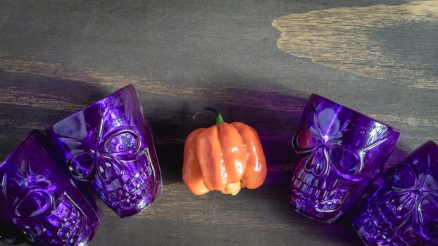 Purple halloween shot glasses, in the shape of a skull, with orange decoration. Halloween Theme.