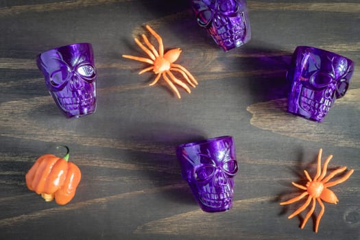 Purple halloween shot glasses, in the shape of a skull, with orange decoration. Halloween Theme.