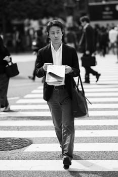 TOKYO, JAPAN - MAY 13, 2019 - A man walks across Shibuya Crossing which is one of the world's most used pedestrian crossings, in central Tokyo, Japan
