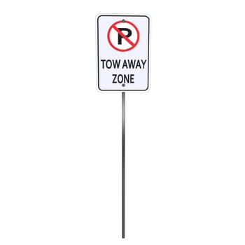 A clear depiction of a no parking tow away zone sign standing prominently beside the road.