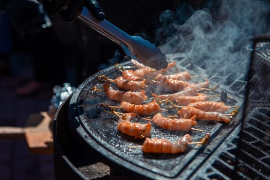 A professional cook prepares shrimps on the grill outdoor, food or catering concept