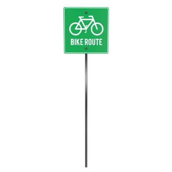 A green bike route sign stands tall, guiding cyclists along a designated path.