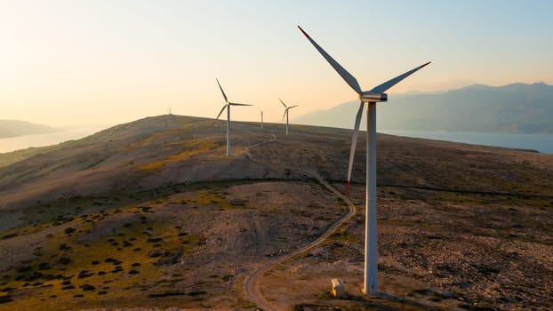 Wind turbines generate eco-friendly power on Pag Island, encircled by the Adriatic Sea at sunset.