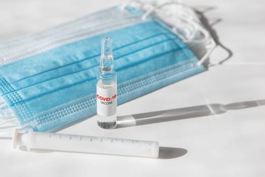 Coronavirus vaccine concept: covid-19 vaccine on the table with blue protective masks.