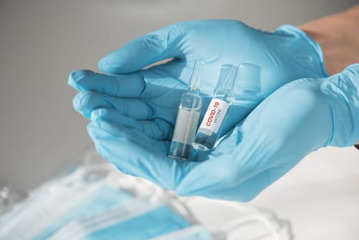 Coronavirus vaccine concept: covid-19 vaccine in doctor hand with blue protective gloves.