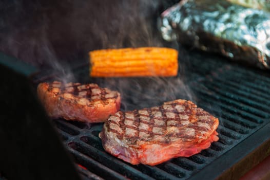 Beef steaks with vegetables on the grill with flames