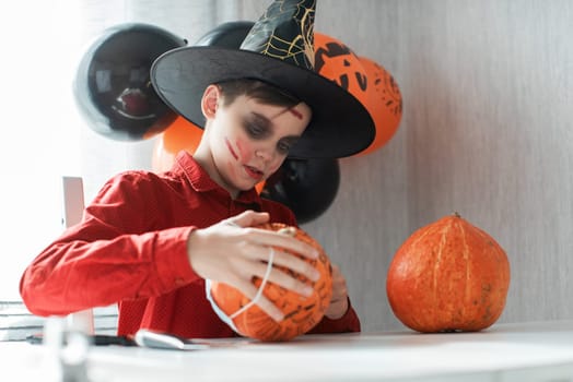Teen boy in costume and face masks to protect against COVID-19 drawing a pumpkin for the Halloween celebration. Halloween carnival with new reality with pandemic concept.