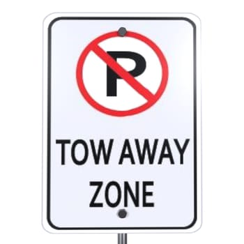A tow away zone sign indicates no parking allowed in an urban area during daylight.