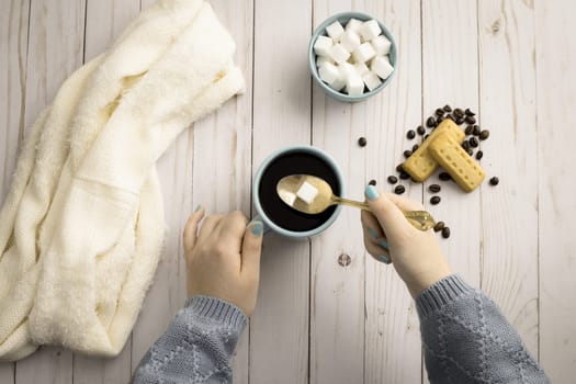 An overview of putting a sugar cube into a cup of black coffee and assorted items on the table.
