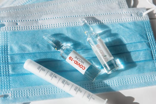 Coronavirus vaccine concept: covid-19 vaccine on the table with blue protective masks.