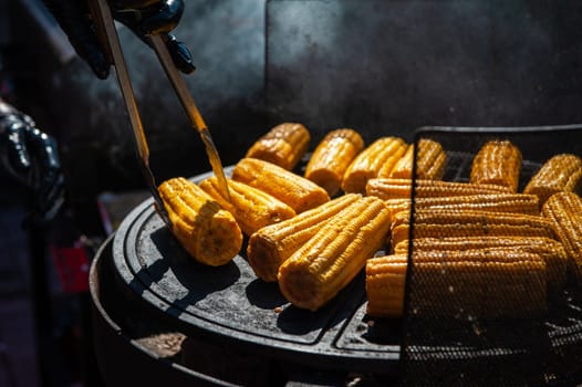 A professional cook prepares corn on the grill outdoor, food or catering concept