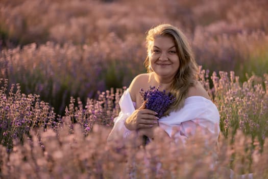 Woman poses in lavender field at sunset. Happy woman in white dress holds lavender bouquet. Aromatherapy concept, lavender oil, photo session in lavender.