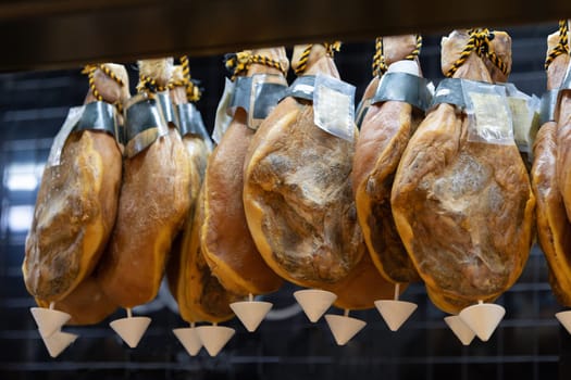 Suspended smoked meat behind a glass case at the market. Mid shot