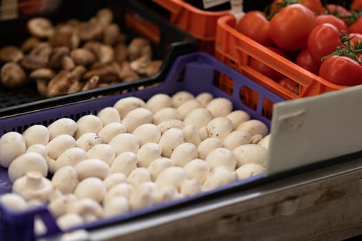 Mushrooms and tomatoes in plastic containers on the market. Mid shot