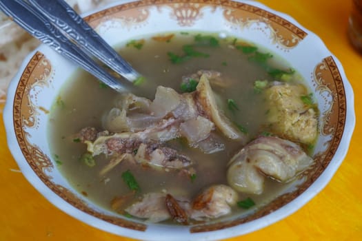A steaming bowl of Soto Iga, a popular Indonesian soup, featuring tender beef ribs, tofu, and a flavorful broth.