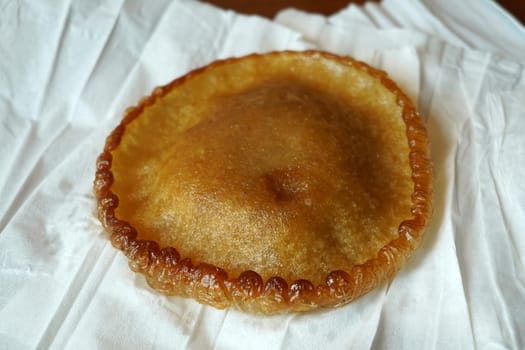 A crispy, golden-brown kue cucur, a traditional Indonesian snack made from rice flour and coconut milk, resting on a white paper napkin