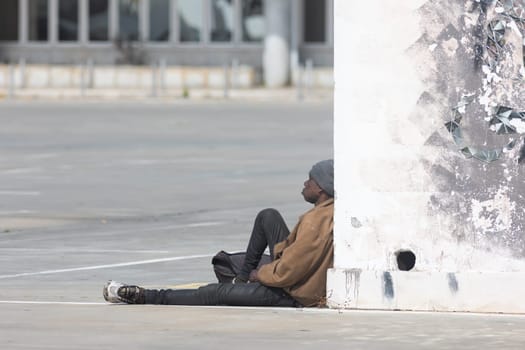 March 12, 2023 Lisbon, Portugal: black homeless person sitting on the street. Mid shot