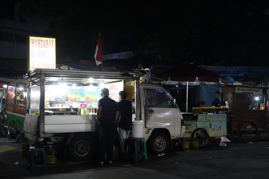 August 14, 2024. Jakarta, Indonesia. A bustling night scene in a corner of the city, filled with street vendors and shoppers.
