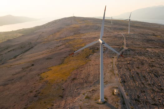 Blades of wind turbines rotate generating power on Pag Island at sunset twilight. Eco-friendly solution to convert wind into power on hill in Croatia