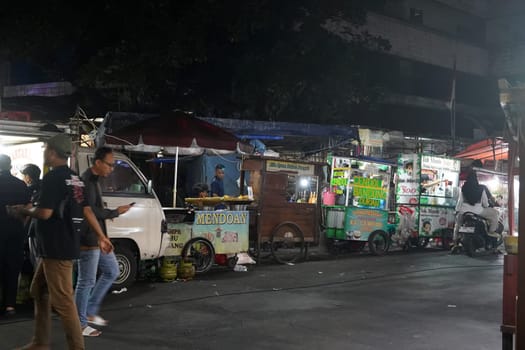 August 14, 2024. Jakarta, Indonesia. A bustling night scene in a corner of the city, filled with street vendors and shoppers.