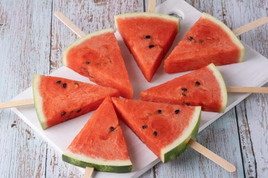 Fresh watermelon slices on sticks with ice.