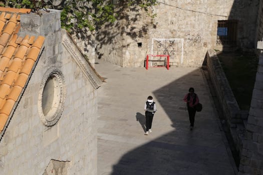 Dubrovnik, Croatia, old town, tiled roof of a house ancient stone building with a triangular facade, top view, people tourists walking April 22, 2023. High quality photo