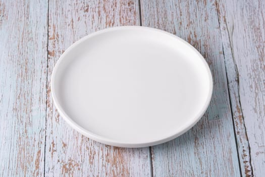 Empty plate on blue wooden background.