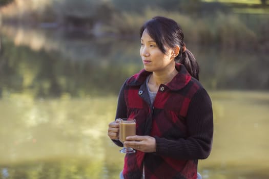 A korean woman enjoys a cup of coffee on a fall day in Spokane, Washington.