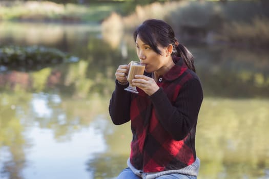 A korean woman enjoys a cup of coffee on a fall day in Spokane, Washington.