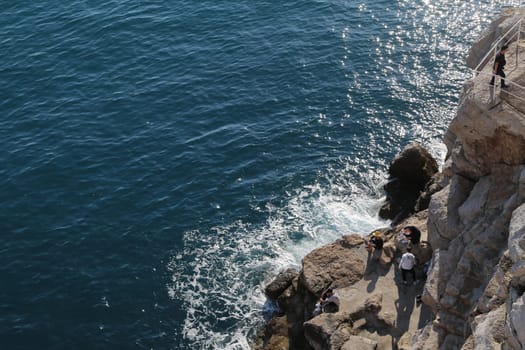 blue water sea, stone cliff, young guy tourist sunbathing, people and nature , summer day Dubrovnik, Croatia April 22, 2023. High quality photo