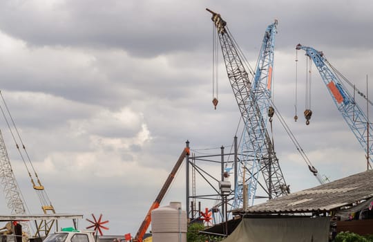Bangkok, Thailand - 31 Aug, 2024 - Latticed boom crawler crane of heavy-duty used for rebuilding bridges near the river in Thailand. Jibs of mobile cranes and telescopic lifting cradles, Tower crane, Construction cranes, Construction and urban development, Space for text, Selective Focus.