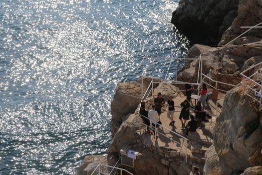 blue water sea, stone cliff, people tourists , nature , summer day Dubrovnik, Croatia April 22, 2023. High quality photo