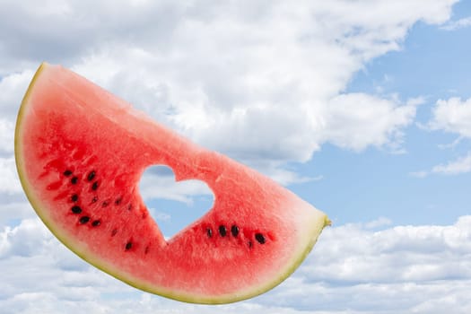 a piece of ripe watermelon against the blue sky