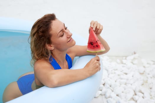 a girl in a bathing suit swims in the pool in a hot summer, a girl with a watermelon, summer holiday concept