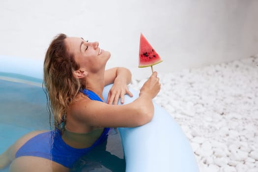 a girl in a bathing suit swims in the pool in a hot summer, a girl with a watermelon, summer holiday concept
