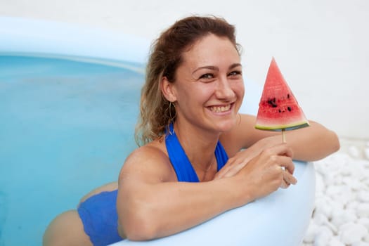 a girl in a bathing suit swims in the pool in a hot summer, a girl with a watermelon, summer holiday concept