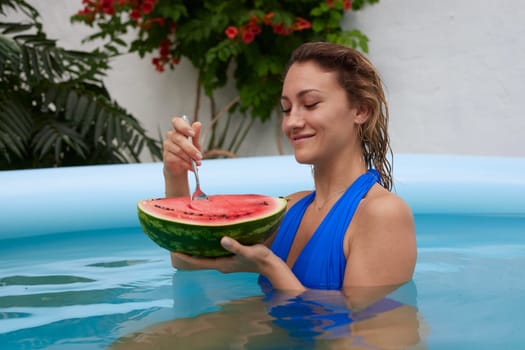 a girl in a bathing suit swims in the pool in a hot summer, a girl with a watermelon, summer holiday concept