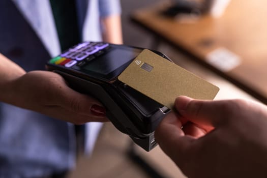 NFC credit card payment. Woman paying with contactless credit card with NFC technology. Wireless money transaction. Card machine in male hand on sunlight background